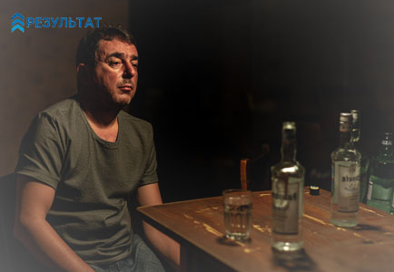 Мужчина сидит и пьет алкоголь